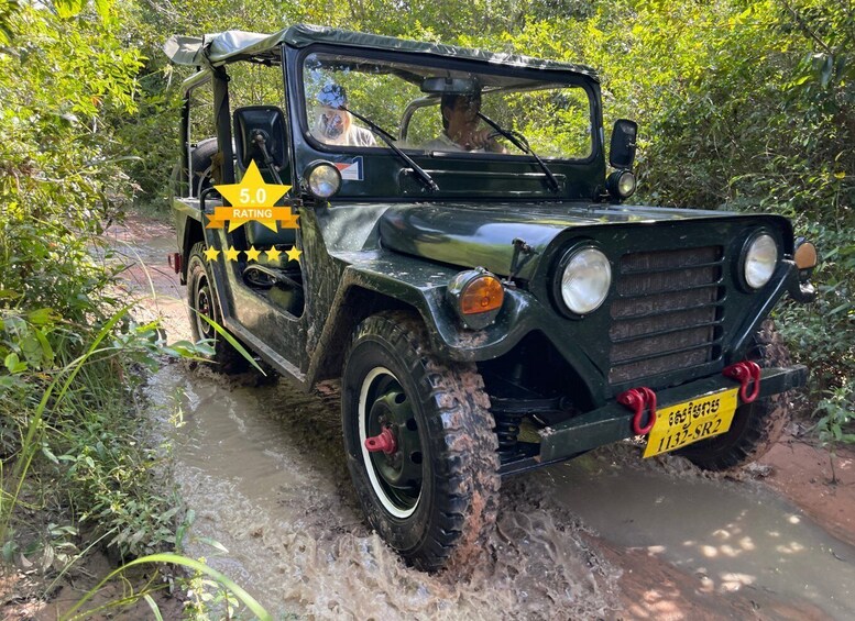 A green off-road vehicle navigating a muddy stream surrounded by dense greenery. 1
