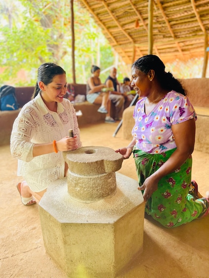 Two women grinding grain using a traditional stone mill. 2