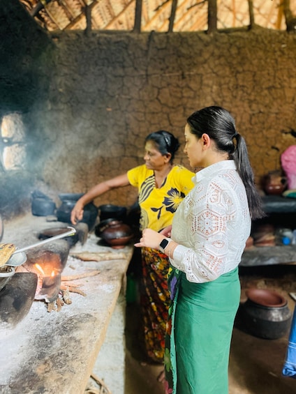 Two women cooking outdoors with a traditional stove and pots. 5