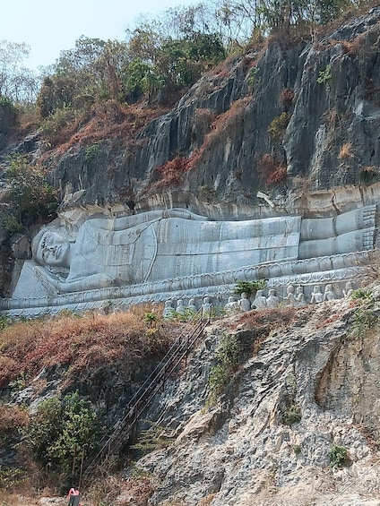 A large stone sculpture of a reclining figure on a hillside. 3