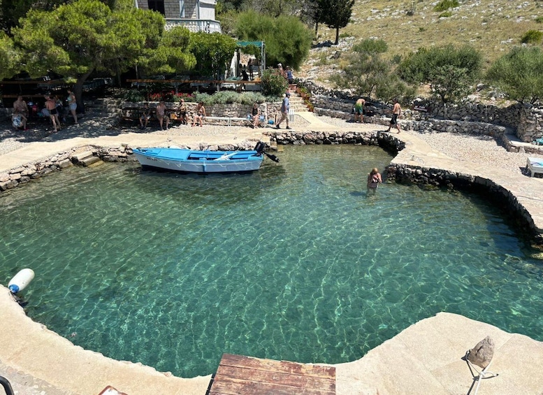A clear blue pool with a boat, surrounded by stone walls and trees. 1