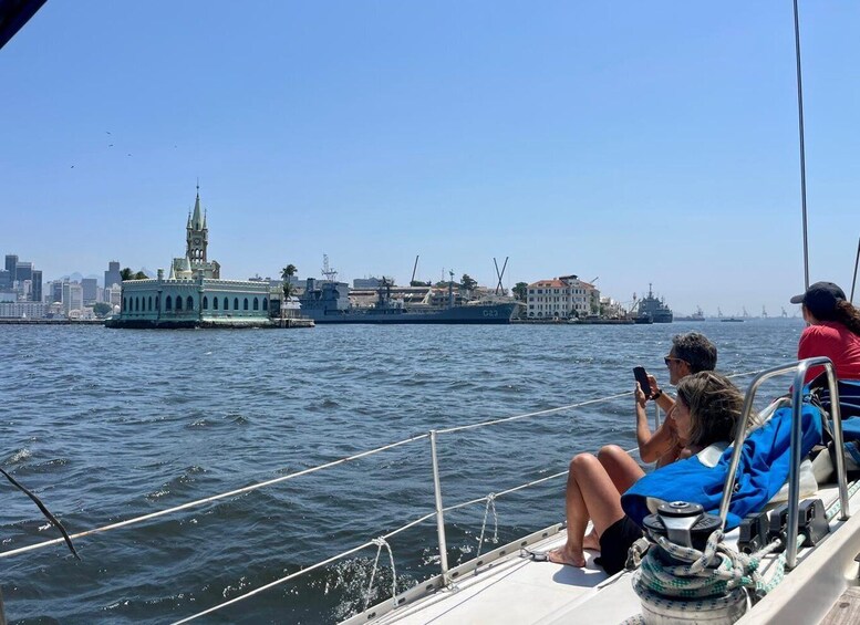 A boat with people on deck, a city skyline, and a large ship in the background. 2