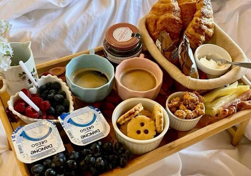 A breakfast tray with croissants, fruits, yogurt, and coffee. 5