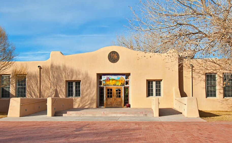 A building with a large entrance, a mural, and a circular emblem above the door. 5