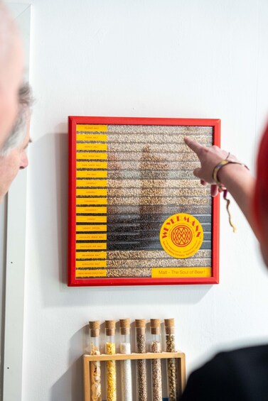A wall with a framed malt chart and a bottle of malt extract. 3