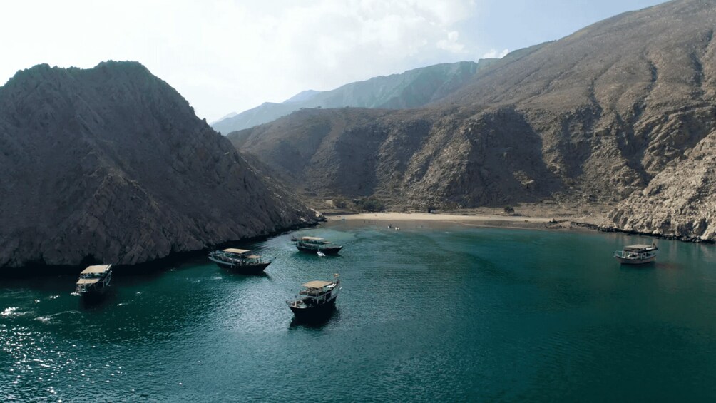 A river flanked by rocky cliffs with boats anchored in the water. 4