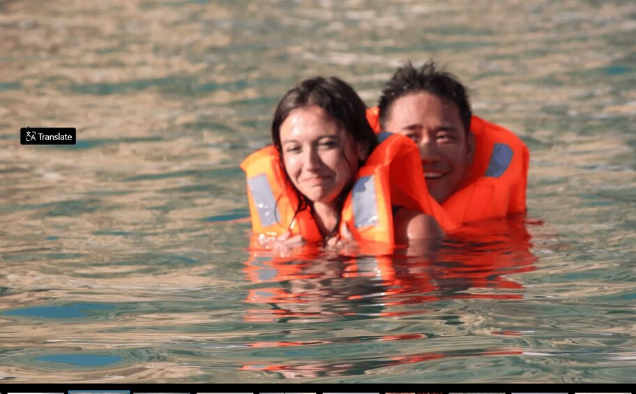 Two people wearing orange life jackets in a body of water. 5