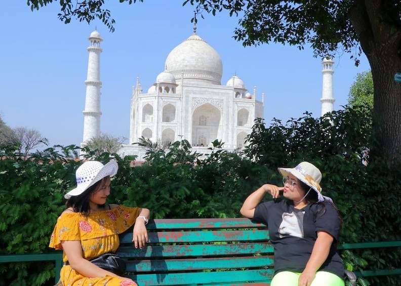 Two people sitting on a bench with the Taj Mahal in the background. 2