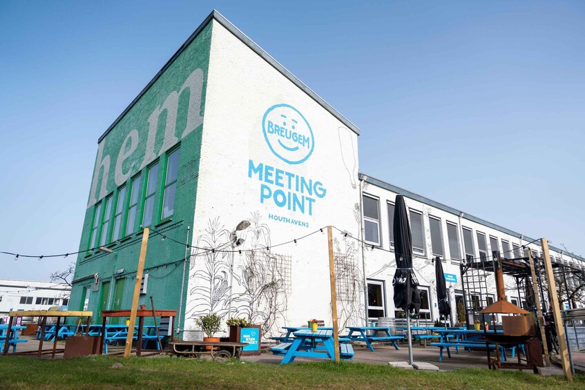 A building with 'BREUGEM MEETING POINT HOUTHAVENS' signage, outdoor tables, and a mural. 2