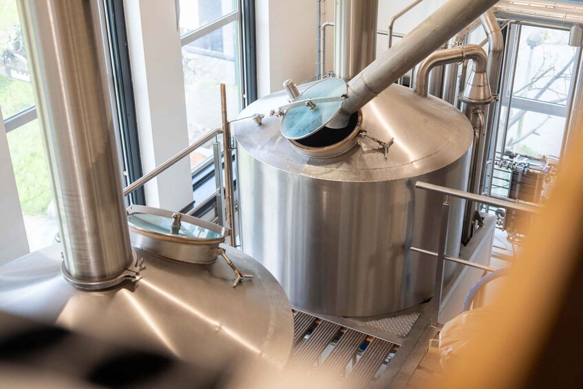 A stainless steel brewing apparatus with a large vessel and connected pipes. 4