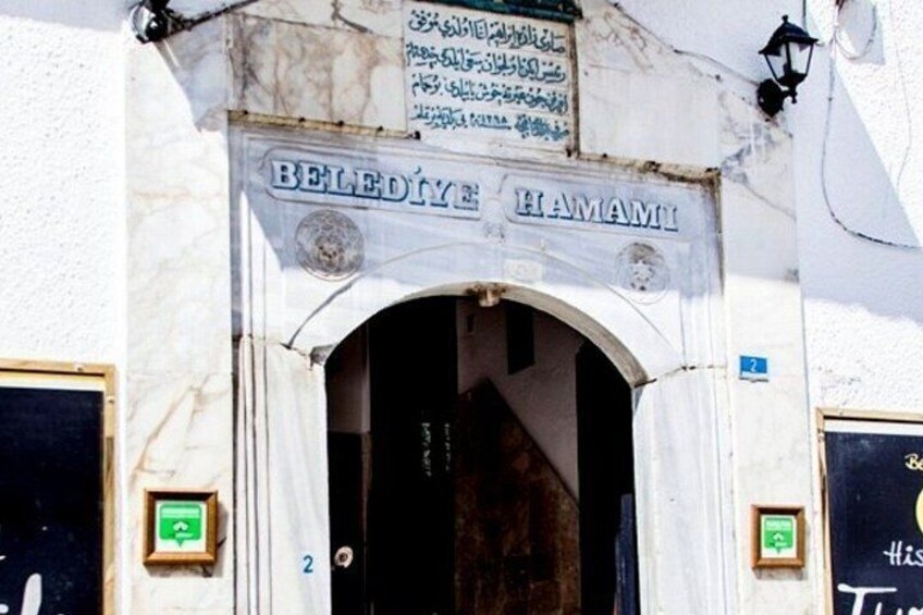 A building entrance with a sign reading 'BELEDİYE HAMAMI' and a number '2' on the door. 3