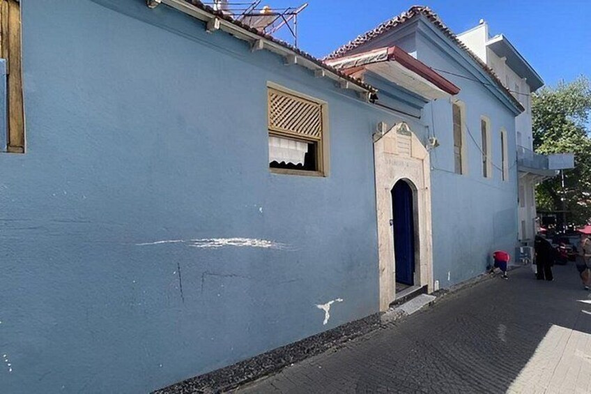 A blue building with a red door, a small window, and a cobblestone street. 2
