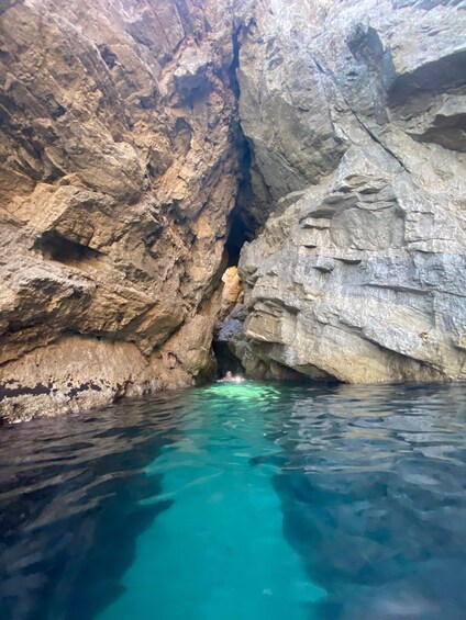 A person swimming in a natural rock formation with clear blue water. 2