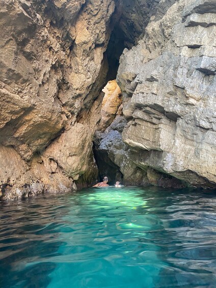 A person swimming in a natural pool surrounded by rocky cliffs. 3