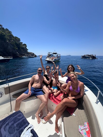A group of people on a boat with rocky cliffs and other boats in the background. 1
