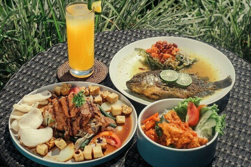 A meal with grilled fish, rice, and vegetables on a woven table outdoors. 3