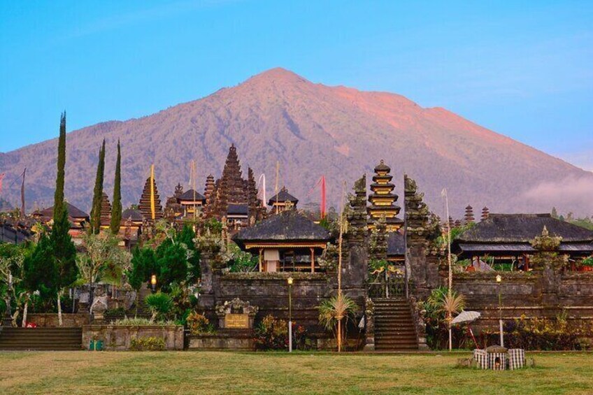 A temple complex with multiple structures, including a prominent stupa, surrounded by lush greenery and a mountain in the background. 5