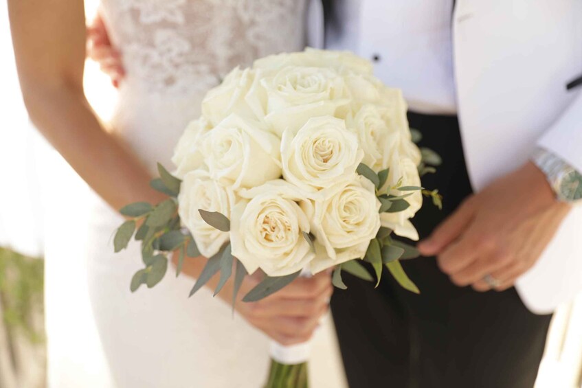 A person holding a bouquet of white roses. 4