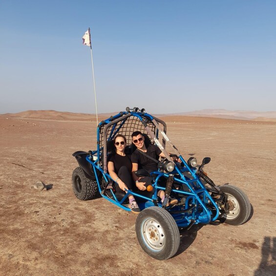 A blue off-road vehicle with a flag, two people, and a desert landscape. 3