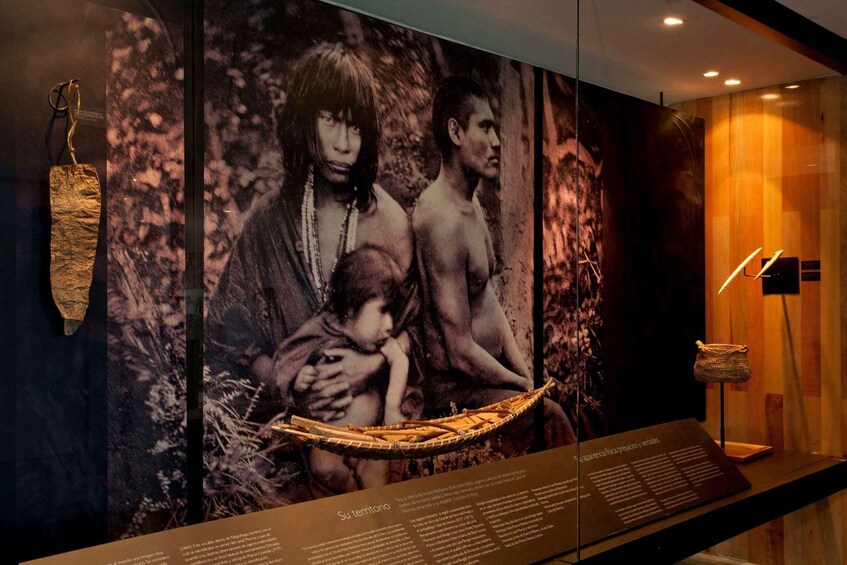 A museum exhibit with a large photograph of a family, a woven boat, and a display panel. 3