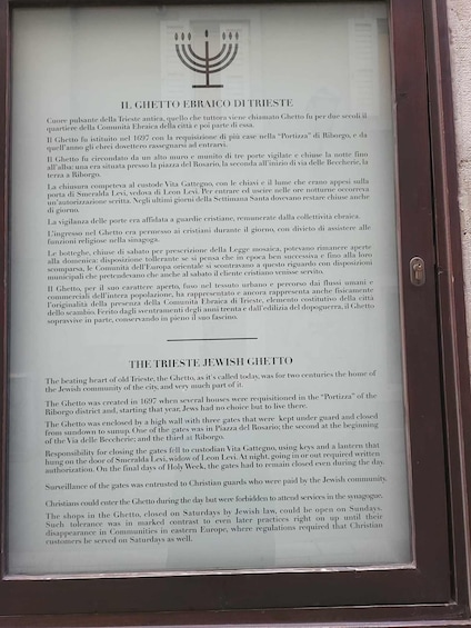 Kehyksiin asetettu historiallinen dokumentti, jonka otsikkona on ’IL GHETTO EBRAICO D’TRIESTE’, ja sen yläpuolella on menorah-symboli. 2