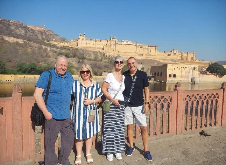 A group of people standing in front of a historic fort with a river in the background. 1