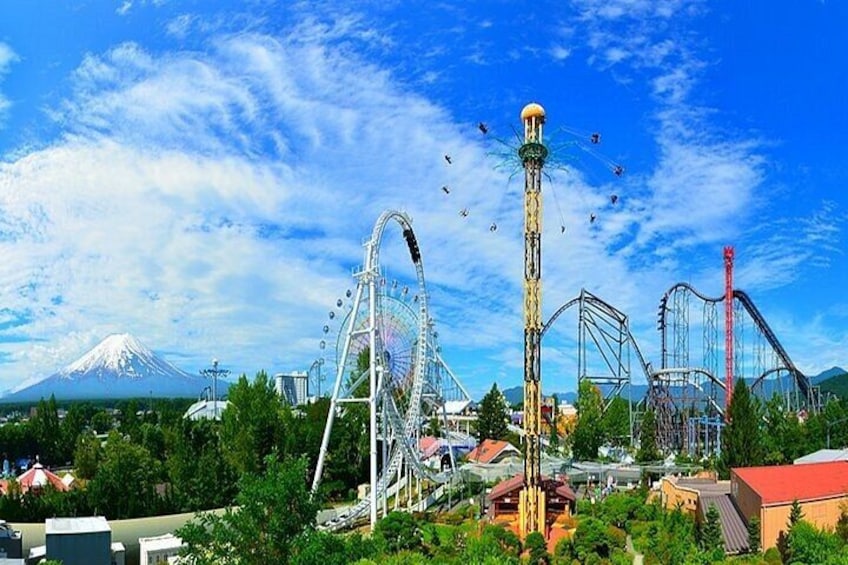 Ein Themenpark mit Achterbahnen, einem Riesenrad und Bergen im Hintergrund. 1