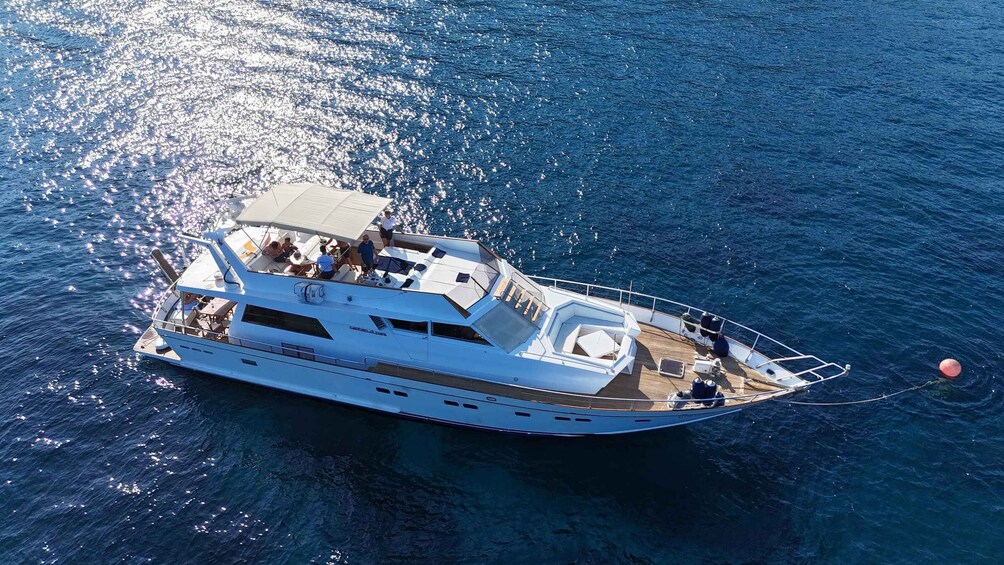 A white yacht with multiple decks and a covered upper deck, anchored in the ocean. 1