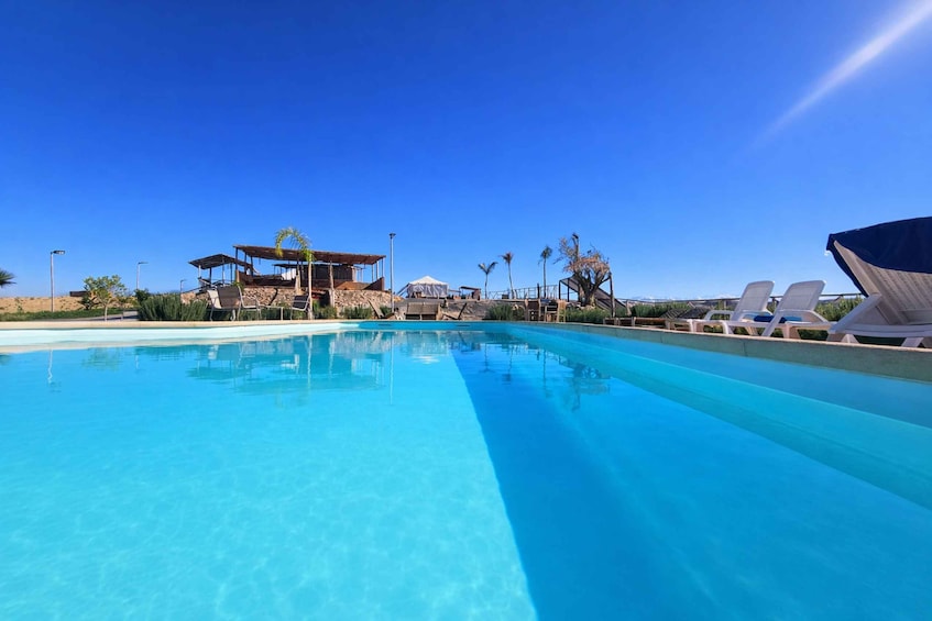 A clear blue pool with lounge chairs and a gazebo. 1