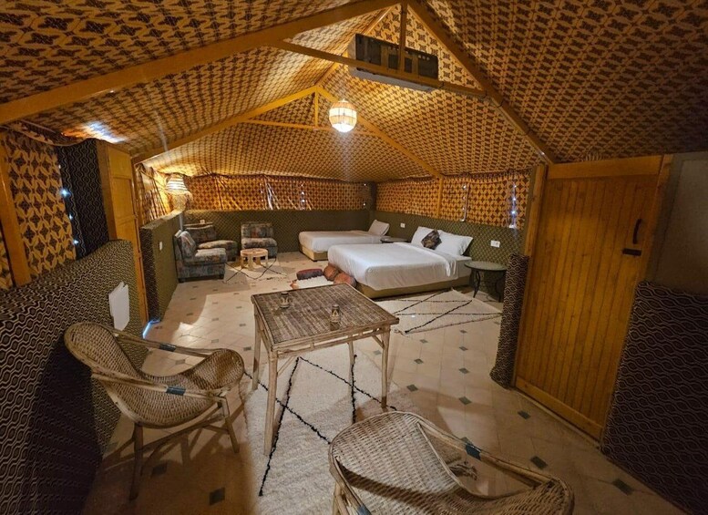 A cozy, patterned tent-style room with a bed, two chairs, a small table, and a hanging light fixture. 5