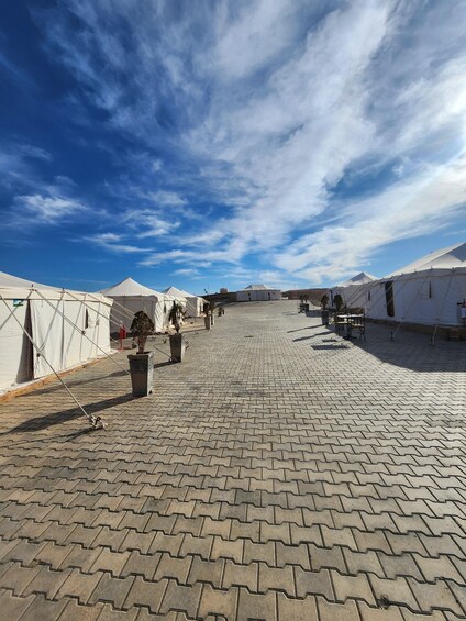A paved courtyard with white tents and potted plants. 2