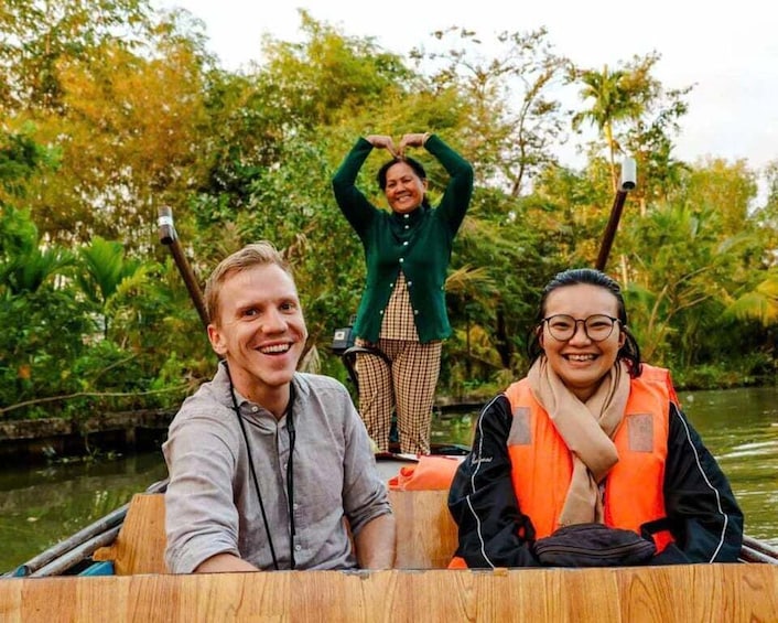 Three people in a boat on a river surrounded by greenery. 1