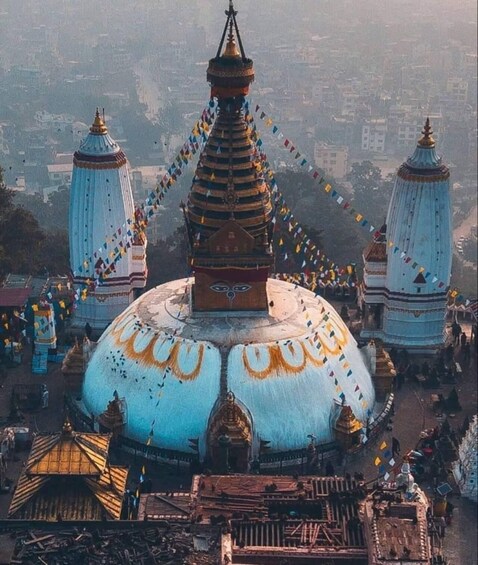 Un vaste temple à plusieurs niveaux, surmonté d’un dôme central et entouré de bâtiments plus petits et de guirlandes de prières aux couleurs vives. 2
