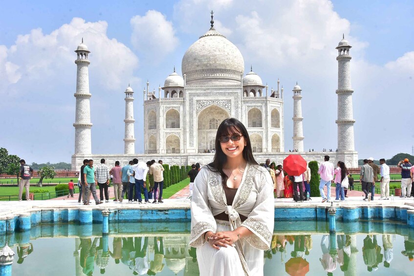 A person standing in front of the Taj Mahal with a reflection in the water. 3