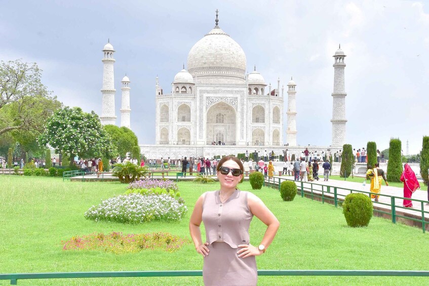 A person standing in front of the Taj Mahal with its four minarets and large dome. 1