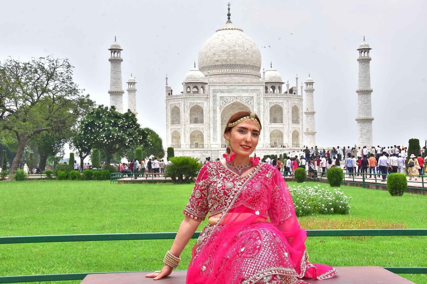 A person in traditional attire seated in front of the Taj Mahal. 2