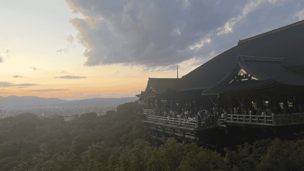 A traditional Japanese building with a large crowd gathered around it, set against a backdrop of mountains and a cloudy sky. 5