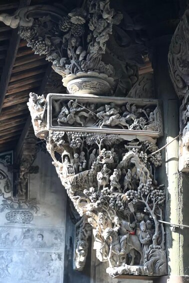 A detailed stone carving of a tree with figures and a pot. 5