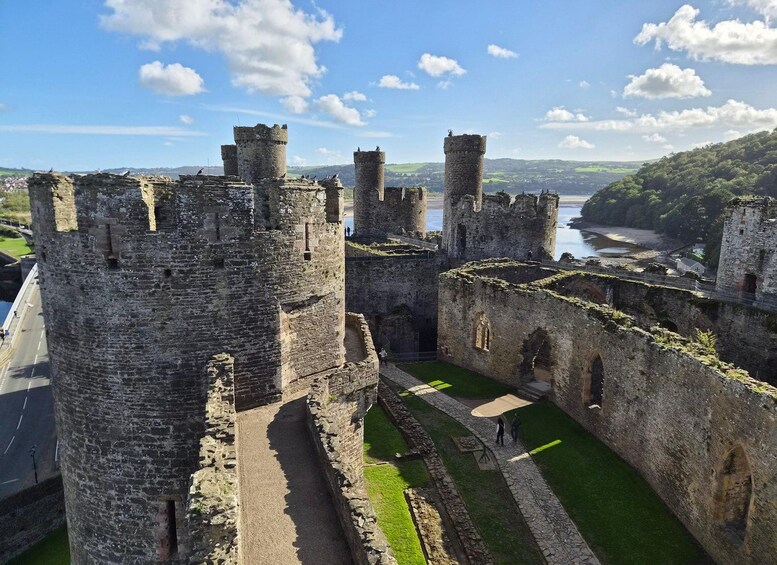 A historic castle with multiple towers, a moat, and a river in the background. 2