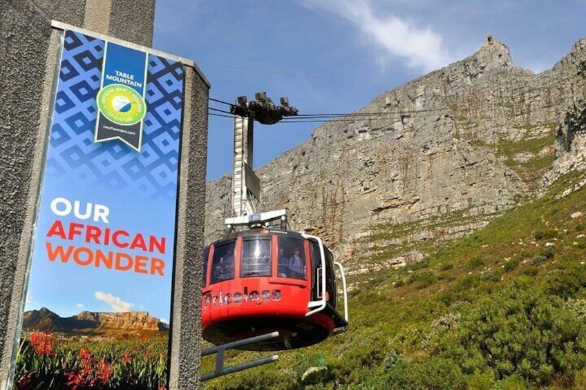 Een kabelbaan bij een bergstation, met een bord waarop staat 'OUR AFRICAN WONDER'. 4