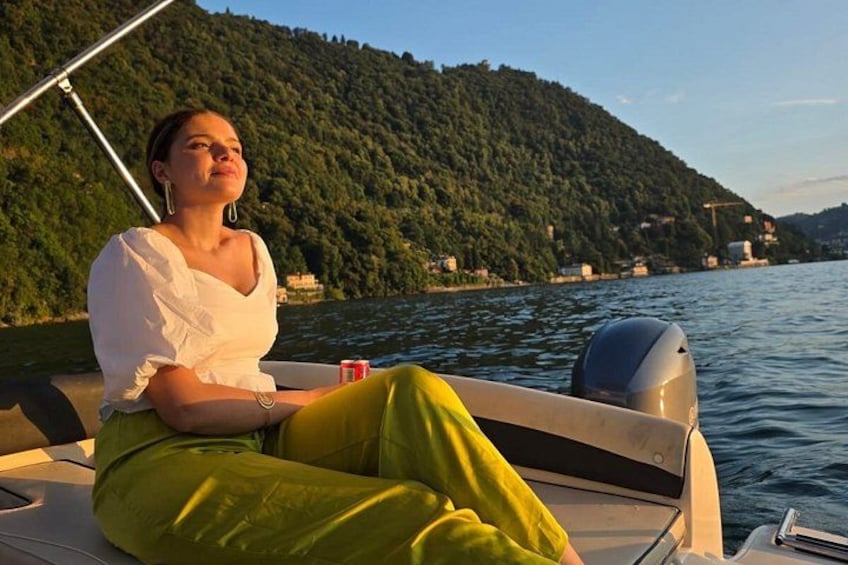 En person sitter i en båt med ett bergigt landskap i bakgrunden. 2