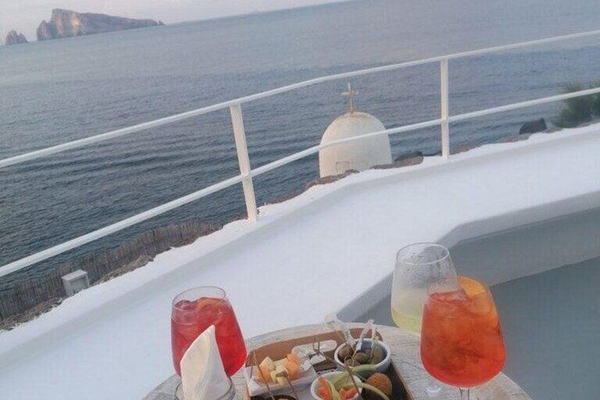 Ett bord med drycker och snacks på en balkong med utsikt över havet. 3