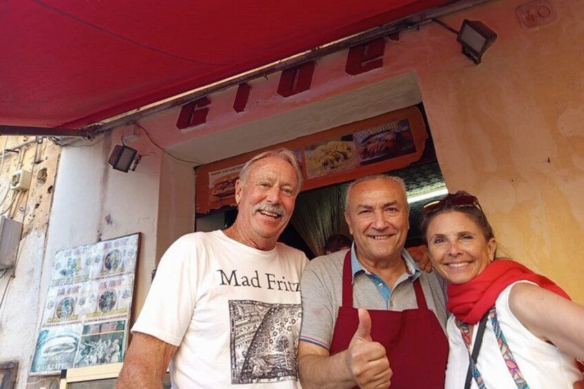 En matstånd med ett rött markis, en menytavla och en person som bär en t-shirt med texten ”Mad Friar”. 5