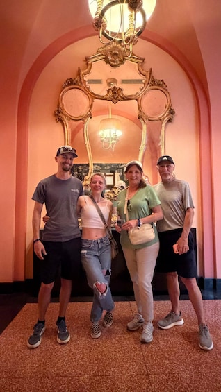 Four people standing in front of an ornate archway with a chandelier. 2
