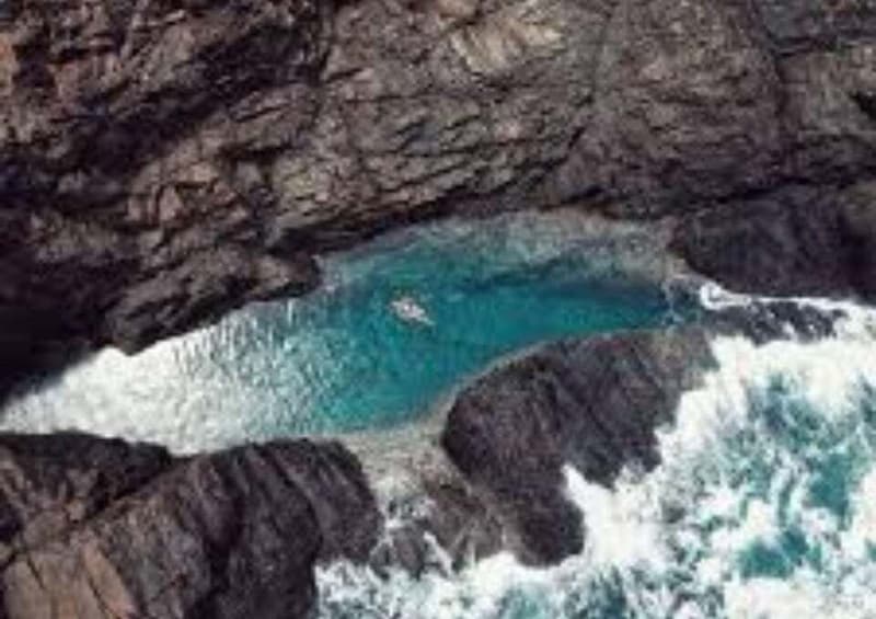 A rocky coastline with a clear blue sea and waves crashing against the rocks. 4