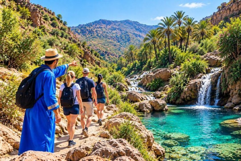 A group of hikers on a rocky trail with a clear blue stream and a waterfall. 4