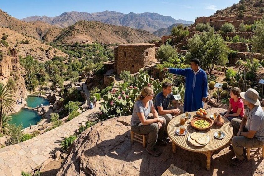 A group of people sitting around a table outdoors with a guide pointing out features of the landscape. 5