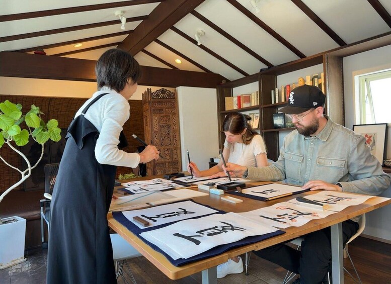 A group of people engaged in calligraphy at a wooden table with ink, brushes, and paper. 2