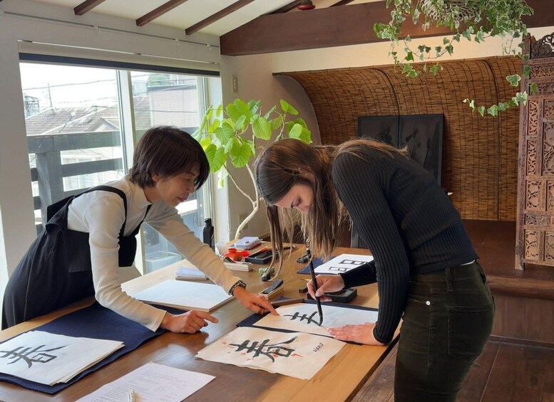 Two people at a wooden table with papers, one writing on a piece of paper and the other pointing at it. 3