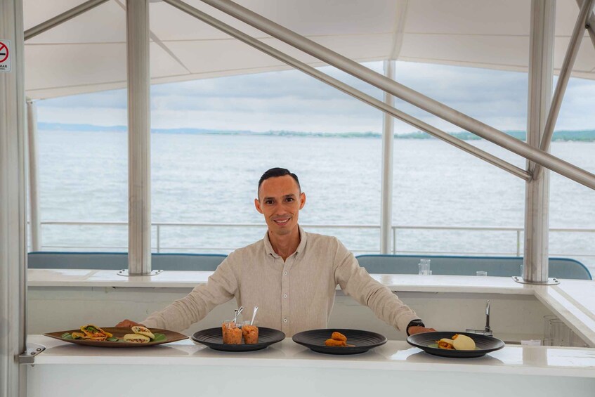 Una persona sentada a una mesa con tres platos de comida en un barco. 1